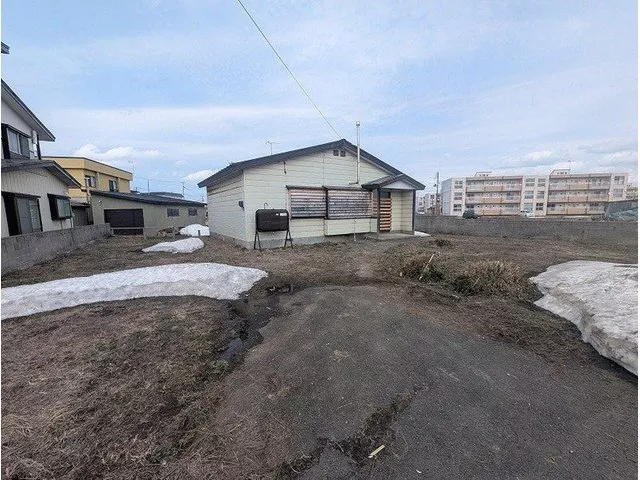 This is a single-story house that needs renovation. It has a large lot with a garden, and items are being removed.